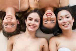 Free photo multiracial group of cheerful young women lying on back