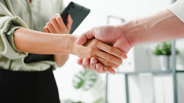 Multiracial group of young creative people in smart casual wear discussing business shaking hands together