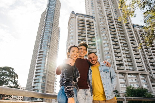 Multiracial young friends standing against city buildings