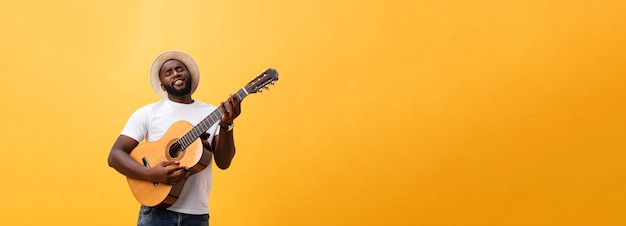 Free Photo muscular black man playing guitar wearing jeans and white tanktop isolate over yellow background