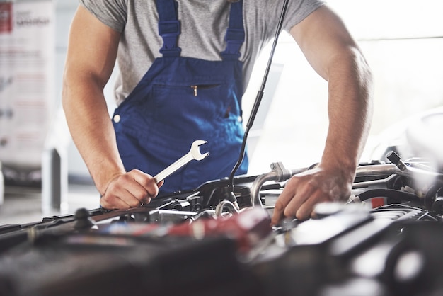 Free photo muscular car service worker repairing vehicle.