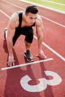 Free photo muscular male young runner on the start line