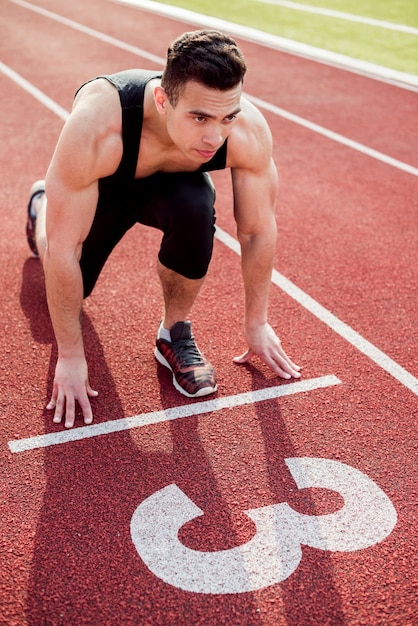 Muscular male young runner on the start line