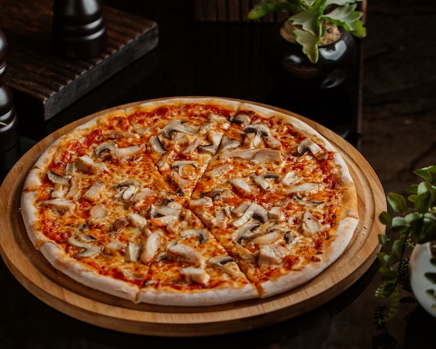 Mushroom pizza with tomato sauce and served in a round bamboo board