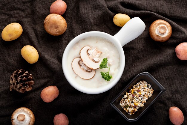 Mushroom soup in a white jar with mushrooms on a black cloth