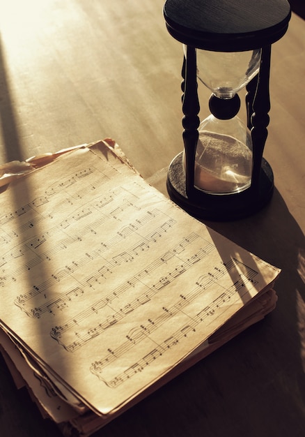 Free photo music notes on papers and hourglass