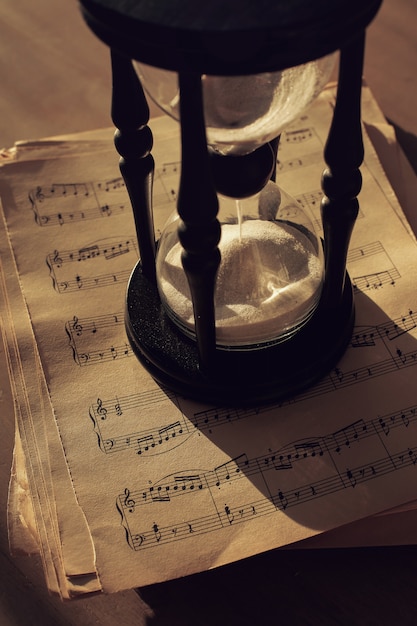 Free photo music notes on papers and hourglass