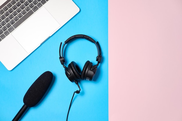 Music or podcast background with headphones microphone coffee and laptop on pink table flat lay Top view flat lay