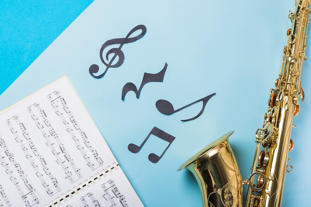 Free photo musical notebook and golden saxophones on blue backdrop