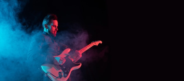 Musician isolated on dark studio in neon light