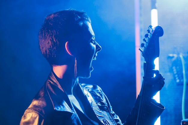 Free photo musician performer holding electric guitar playing heavy metal song in studio preparing rock performance for grunge concert. beautiful guitarist working at punk album, checking instrument sound