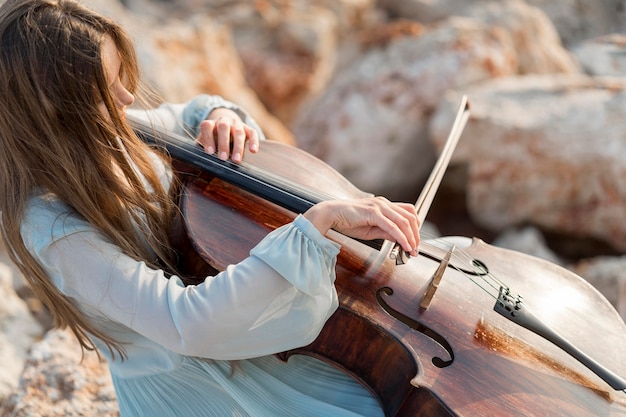 Musician playing cello on rocks