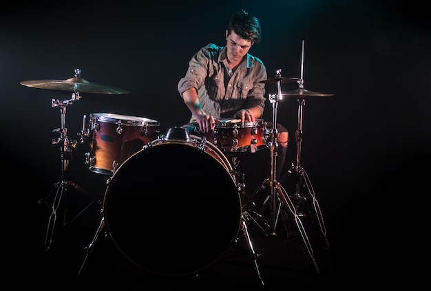 Free photo musician playing drums, black background and beautiful soft light, emotional play, music concept