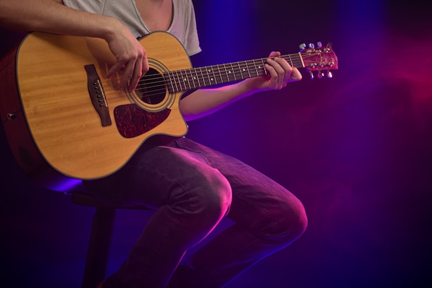 The musician plays an acoustic guitar.