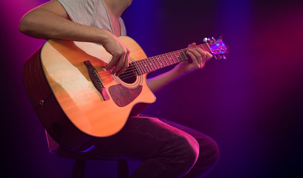 The musician plays an acoustic guitar.