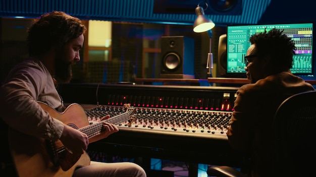 Musician and sound engineer recording guitar tunes in control room