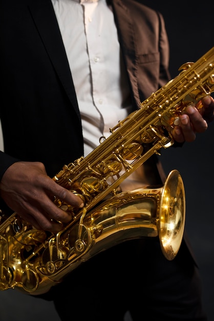 Free Photo musician in suit holding saxophone close up