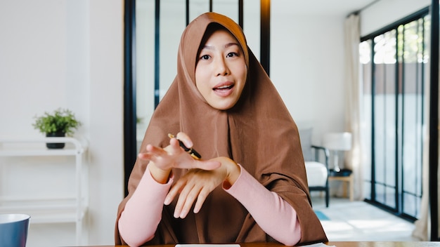 Free photo muslim lady wear hijab using computer laptop talk to colleagues about plan in video call meeting while remotely work from home at living room.