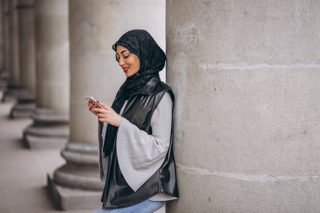 Muslim woman using phone outside in the street