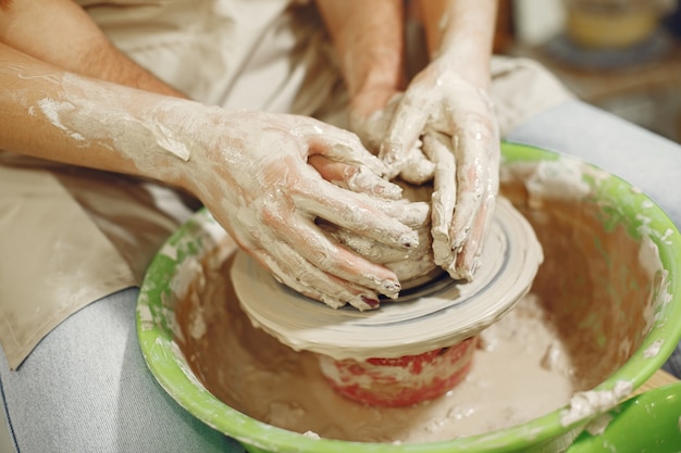 Free photo mutual creative work. hands creating a bowl on a pottery wheel in a clay studio.