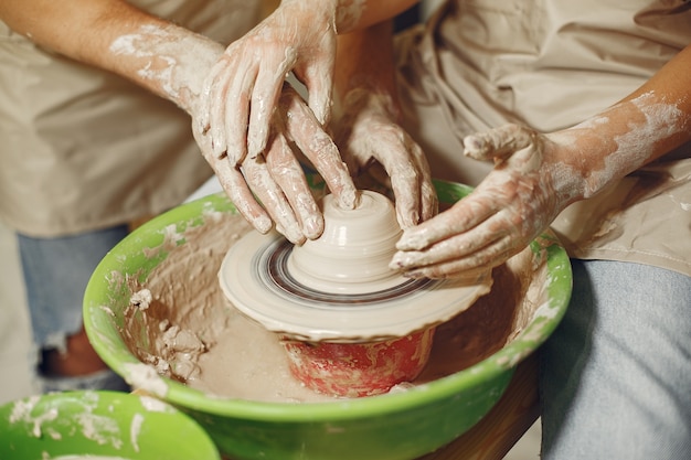 Mutual creative work. Hands creating a bowl on a pottery wheel in a clay studio.