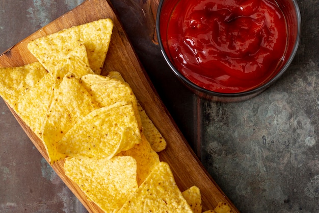 Nachos on cutting board and tomato sauce