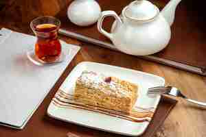 Free photo napoleon cake with butter cream sugar powder and dark tea on table