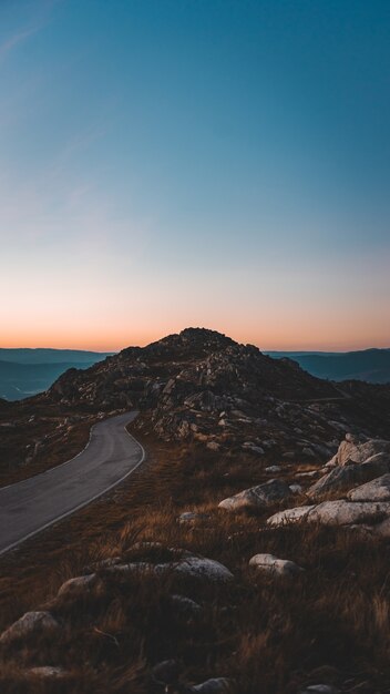 Free photo narrow road leading to a rocky cave under the beautiful sunset sky