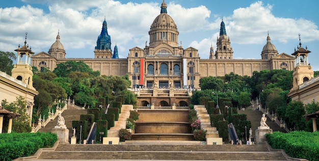 The National Palace in Barcelona, Spain gardens and people in front of it. Cloudy sky