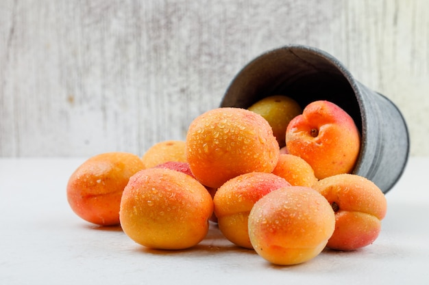 Free photo natural apricots in a mini bucket. side view.