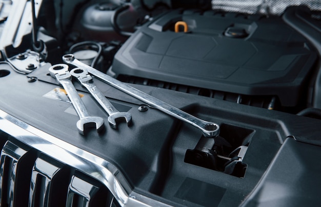 Natural daylight. Repair tools lying down on the engine of automobile under the hood