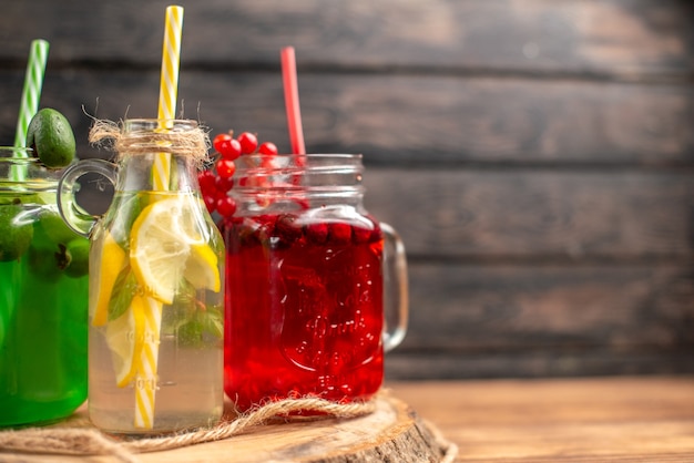 Natural organic fuit juices in bottles served with tubes on a wooden cutting board