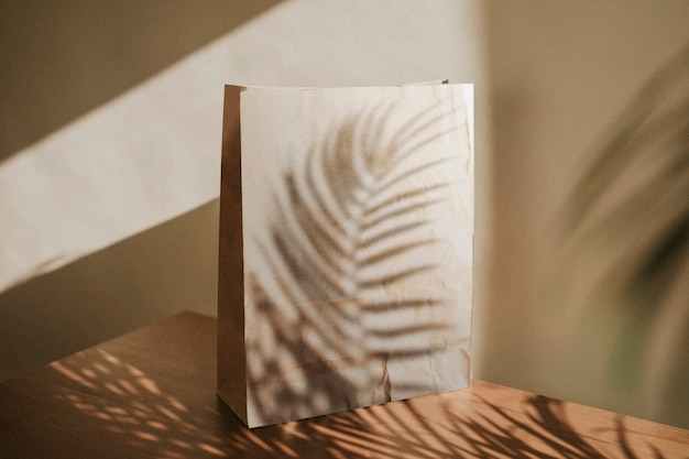 Free Photo natural paper bag with palm leaves shadow