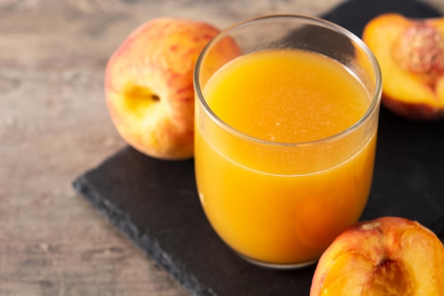 Natural peach juice in glass on wooden table