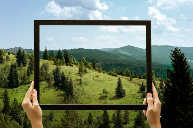 Free photo nature landscape with hand holding frame