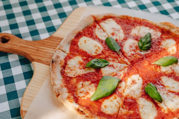 Neapolitan pizza with ham, cheese, arugula, basil, tomatoes sprinkled with cheese 