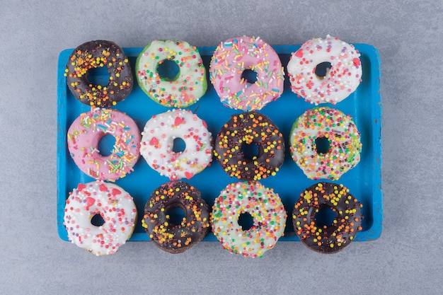 Free photo neatly arranged donuts on a platter on marble surface