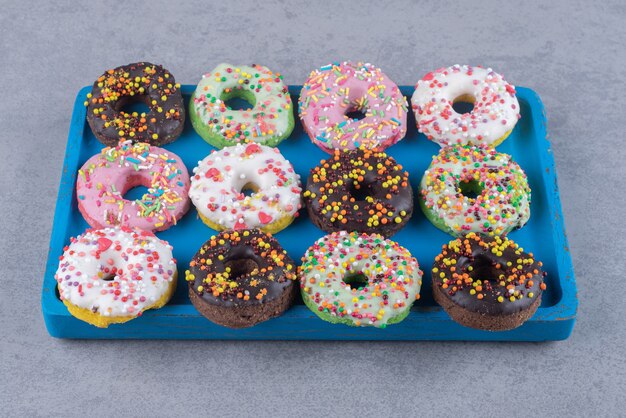 Neatly arranged donuts on a platter on marble surface