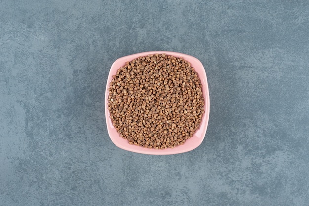 Neatly heaped bowl of buckwheat on marble background. High quality photo