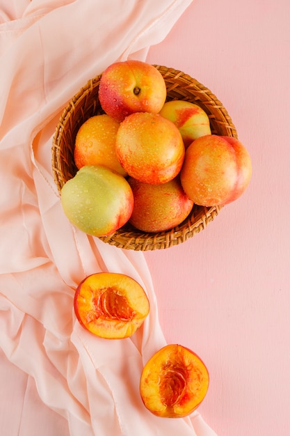 Free Photo nectarines in a basket top view on pink and textile surface