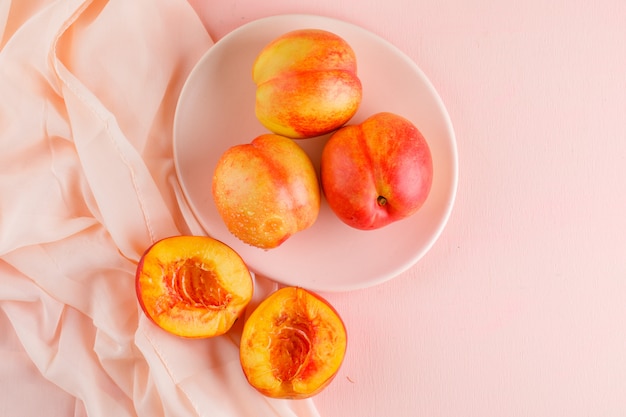 Free Photo nectarines in a plate on pink and textile surface. flat lay.