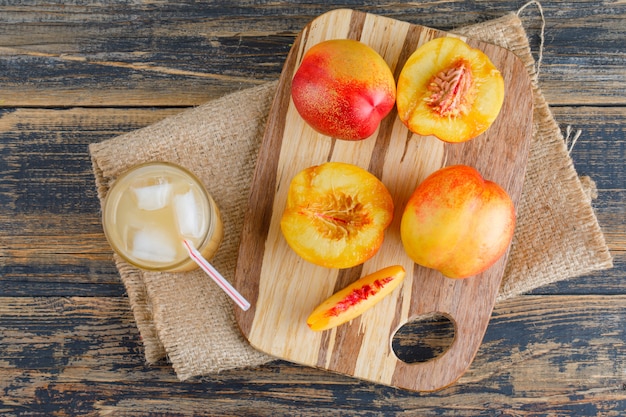 Free photo nectarines with cutting board, juice on wooden and piece of sack