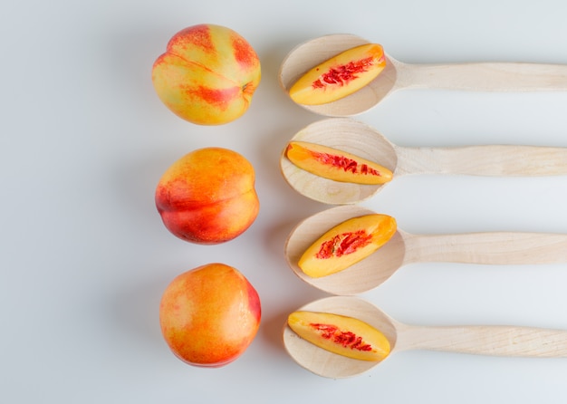 Free photo nectarines in wooden spoons on a white table