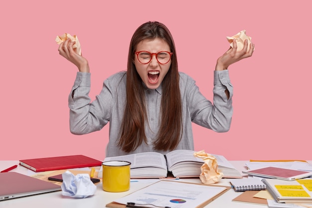 Free photo negative emotions, paper work and studying concept. outraged beautiful lady frowns face, shouts loudly