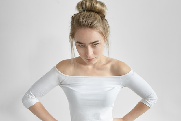 Free photo negative human facial expression and reaction. isolated shot of angry annoyed young woman wearing open shoulder top looking sullenly