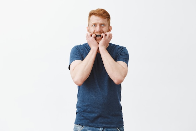 Free photo nervous and anxious scared attractive masculine guy with ginger hair, biting fingernails, staring frightened