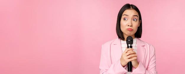 Free Photo nervous female entrepreneur giving speech with microphone holding mic and looking aside anxiously po