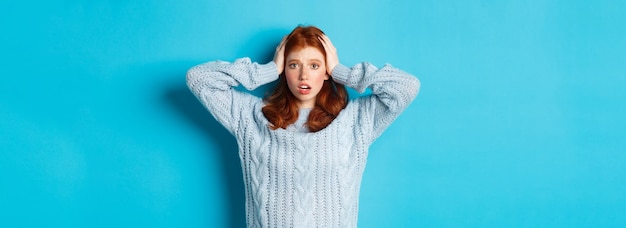 Free photo nervous redhead girl standing overwhelmed holding hands on head in panic and staring at camera stand