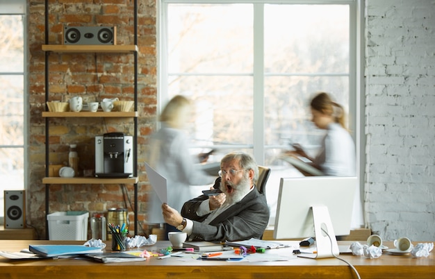 Free Photo nervous and tired boss at his workplace busy while people moving near blurred. office worker, manager working, has problems and deadline, his colleagues distracting. business, work, workload concept.