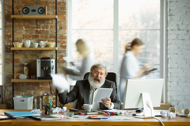 Free photo nervous and tired boss at his workplace busy while people moving near blurred. office worker, manager working, has problems and deadline, his colleagues distracting. business, work, workload concept.